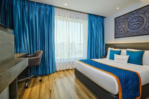 a bedroom with a large bed with blue curtains at Zone By The Park Pathankot in Pathānkot