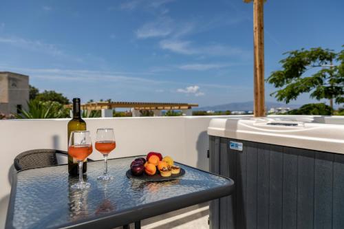 a table with two glasses of wine and a plate of fruit at Irida Vacation suites in Kastraki Naxou