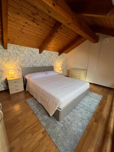 a bedroom with a large white bed and wooden ceilings at V HOME in Biella