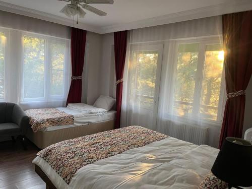 a bedroom with two beds and windows with red curtains at Sarı Konak Butik Otel in Gure