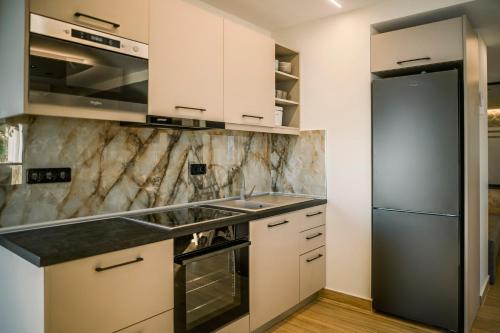 a kitchen with white cabinets and a stainless steel refrigerator at Black Rocks Luxury Seafront Beach Suite in Agios Gordios