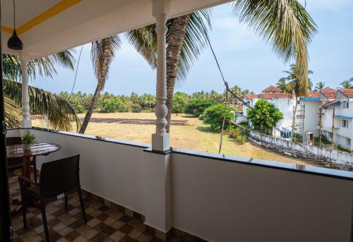 a balcony with a table and a palm tree at The Woodside Inn in Benaulim