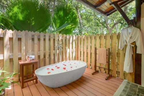 a bath tub sitting on a deck with a fence at JA Enchanted Island Resort Seychelles in Round Island