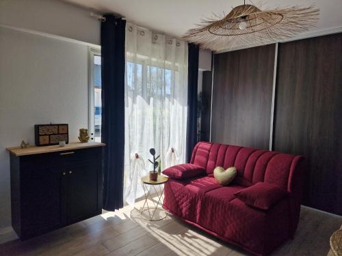 - un canapé rouge dans le salon doté d'une fenêtre dans l'établissement Studio Guérande, à Guérande