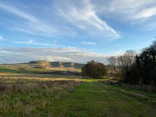 a dirt road in a field with hills in the background at Eclectic Barn - Pergola & Dog-Friendly Garden in Calne
