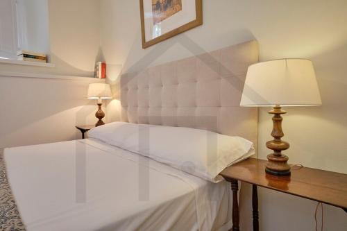 a bedroom with a white bed and a table with a lamp at Casona del Sol El Retorno I in Lastres