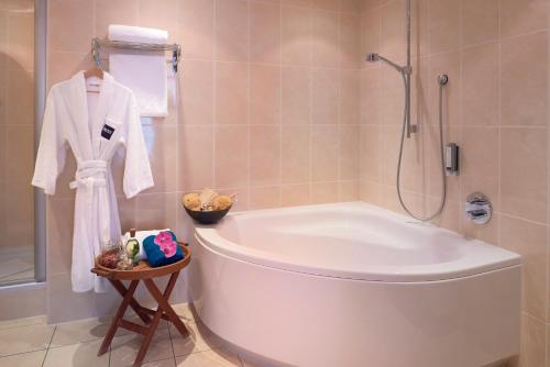 a bathroom with a white tub and a shower at Dorint Hotel am Dom Erfurt in Erfurt