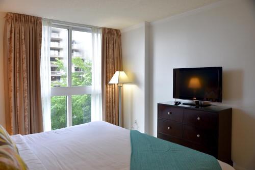 een slaapkamer met een bed, een tv en een raam bij Relaxing Condo Hotel In The Grove, Free Parking in Miami