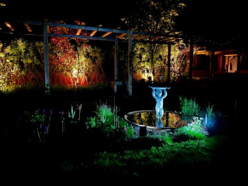 a fountain in the middle of a garden at night at Eclectic Barn - Pergola & Dog-Friendly Garden in Calne