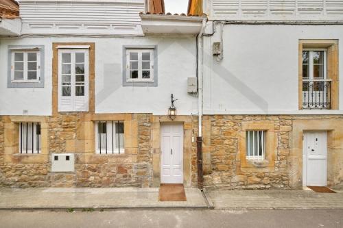 a stone building with a white door and windows at Casona del Sol El Retorno I in Lastres