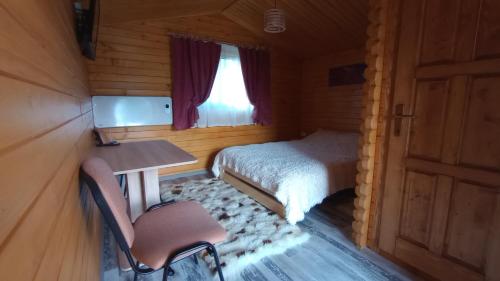 ein kleines Schlafzimmer mit einem Bett, einem Schreibtisch und einem Fenster in der Unterkunft Casa Fericirii in Cîrţişoara