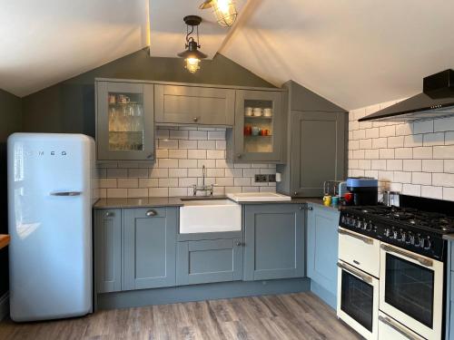 een keuken met blauwe kasten en een witte koelkast bij High Street Apartment in Windermere
