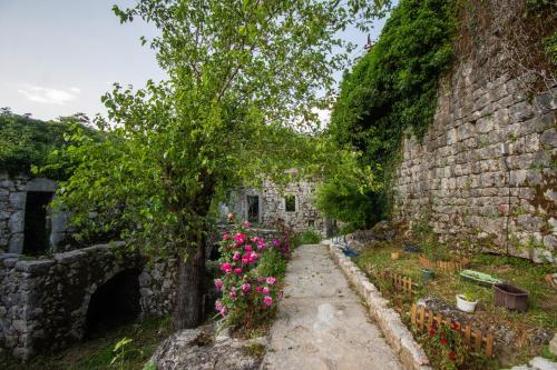 an old stone wall with flowers and a tree at centuries old Ethno House Đurović in Virpazar