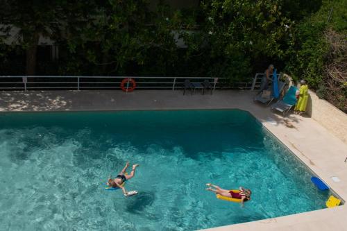 twee mensen zwemmen in een zwembad bij Stefanakis Hotel & Apartments in Varkiza