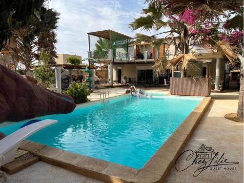 einen Pool in einem Resort mit Palmen in der Unterkunft Chez Lilie Maison d'hôtes à Saly in Saly Portudal