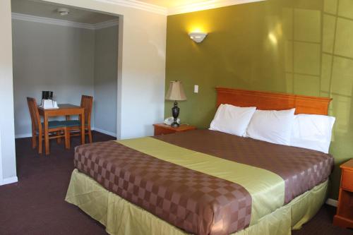 a hotel room with a large bed and a table at West Coast Inn Santa Ana in Santa Ana