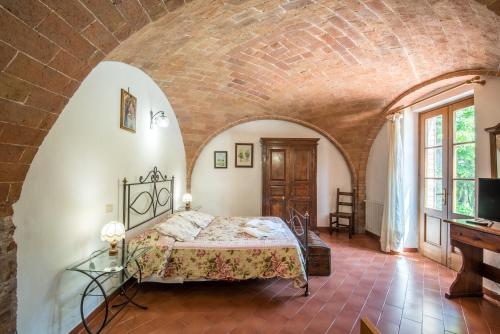 um quarto com uma cama e uma parede de tijolos em Appartamento Sangiovese em Montepulciano