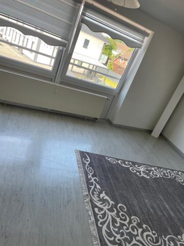 an empty living room with two windows and a rug at Ferienwohnung in Celle