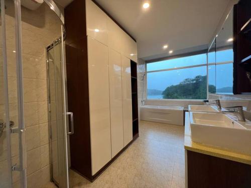a bathroom with two sinks and a shower with a window at The Dream Villa Best Lake View in Xuan An