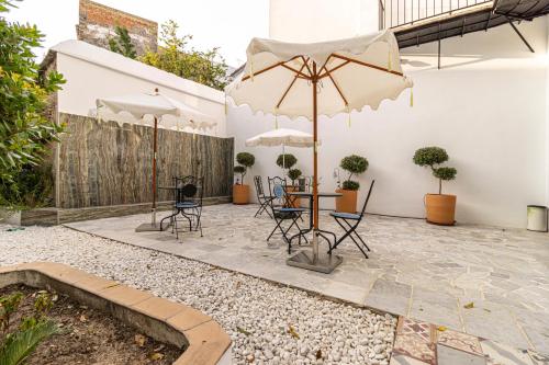 a patio with a table and chairs and umbrellas at Casa Palacio Rufina & Jardines in Jerez de la Frontera
