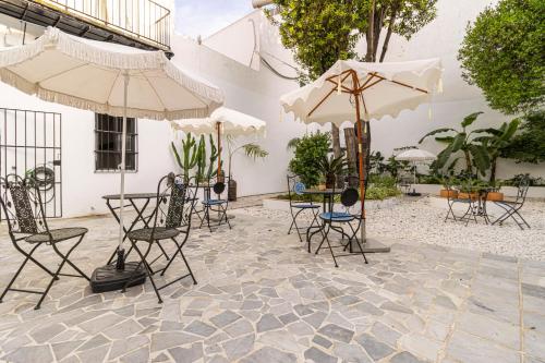 un patio con sedie, tavoli e ombrelloni di Casa Palacio Rufina & Jardines a Jerez de la Frontera