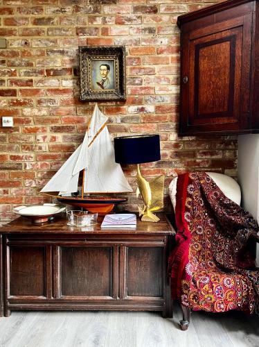 a desk with a lamp and a chair next to a brick wall at Eclectic Barn - Pergola & Dog-Friendly Garden in Calne
