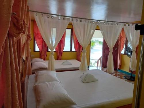 a couple of beds in a room with curtains at Chilly Beach Resort Palawan in Aborlan