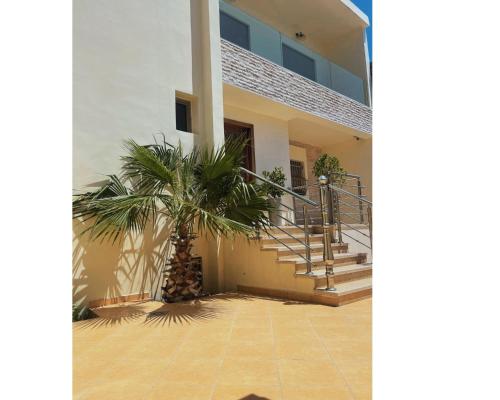 una palmera frente a un edificio con escaleras en Villa de Luxe - Agadir City, en Agadir