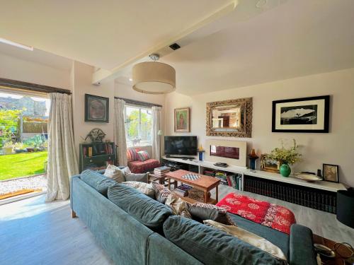 a living room with a blue couch and a tv at Eclectic Barn - Pergola & Dog-Friendly Garden in Calne