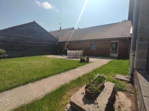 a yard with a house and a patio at Gîte des trois petits oiseaux in Picarreau
