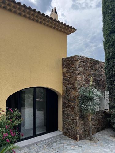 a yellow house with a glass door and a stone wall at Villa familiale avec vue imprenable in Saint-Raphaël