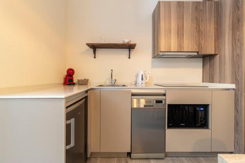 a small kitchen with stainless steel appliances and wooden cabinets at Casa Palacio Rufina & Jardines in Jerez de la Frontera
