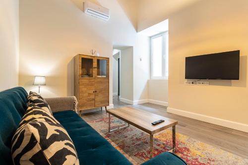 a living room with a couch and a tv at Casa Palacio Rufina & Jardines in Jerez de la Frontera
