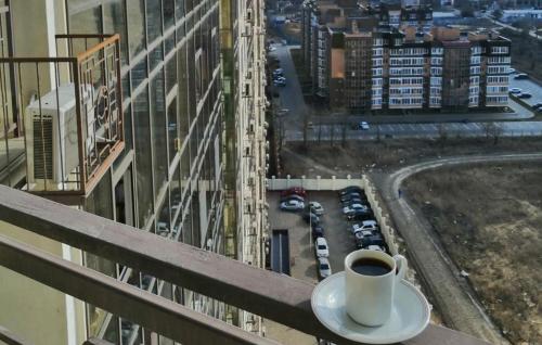 a cup of coffee sitting on the ledge of a building at Апартаменты на Марсельской, Кадорр, 4я Жемчужина in Odesa