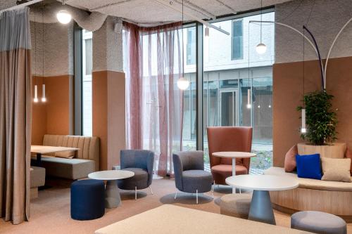a lobby with tables and chairs and windows at ibis budget Gent Centrum Dampoort in Ghent