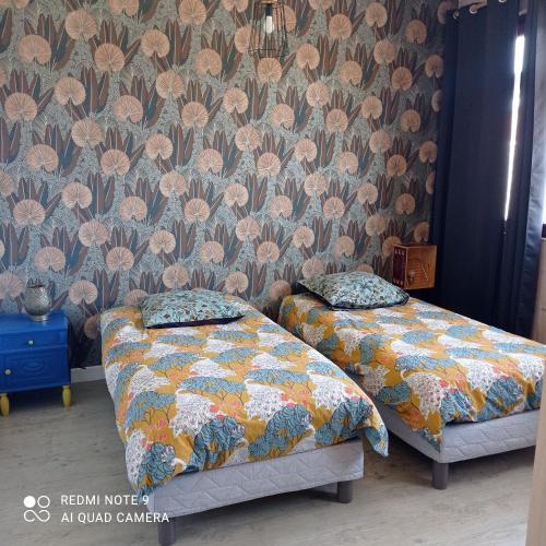 2 camas en una habitación con papel pintado floral en Le Clair centre ville, en Langon