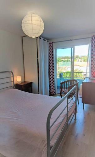 une chambre avec un lit blanc et une grande fenêtre dans l'établissement La Ciotat, appartement rénové en bord de mer, à La Ciotat