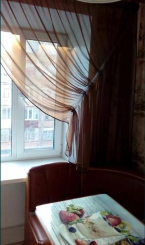 un tavolo davanti a una finestra con tenda di 1 комнатная квартира a Rudny