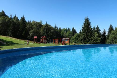 een blauw zwembad met een speeltuin op de achtergrond bij Relax hotel Bára Benecko in Benecko