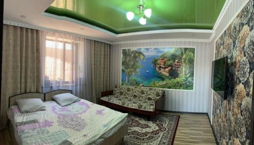 a bedroom with a bed and a painting on the wall at KF_Guest House-Madina in Shabdan