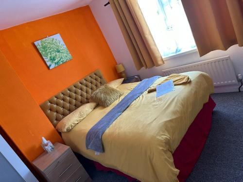 1 dormitorio con 1 cama con pared de color naranja en Quick Stop Night Stay - Gatwick, en Crawley