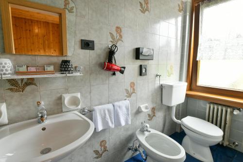 a bathroom with a tub and a toilet and a sink at Guesthouse Rosengarten in Dobbiaco