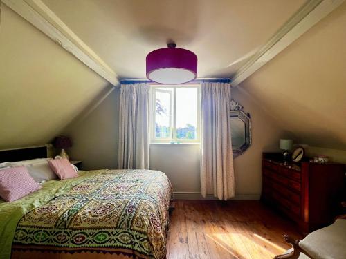 a bedroom with a large bed and a window at Eclectic Barn - Pergola & Dog-Friendly Garden in Calne