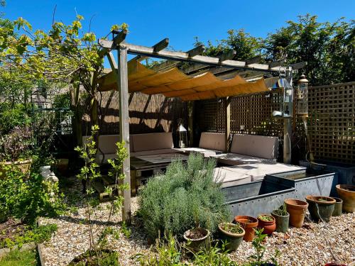 a garden with a pergola and chairs and plants at Eclectic Barn - Pergola & Dog-Friendly Garden in Calne