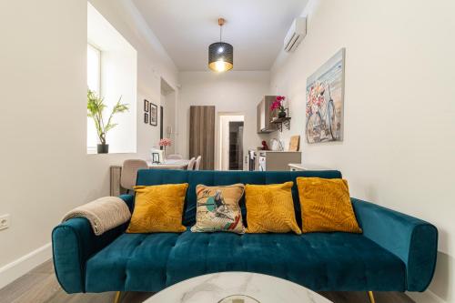 a blue couch with yellow pillows in a living room at Casa Palacio Rufina & Jardines in Jerez de la Frontera