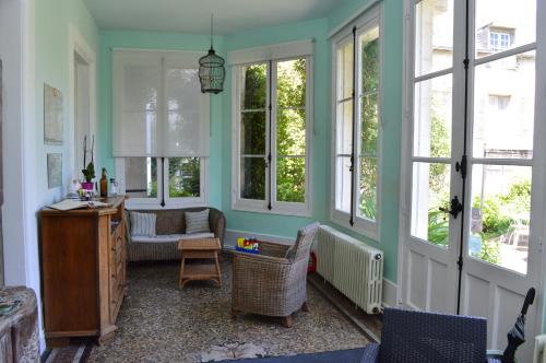 un salon avec un canapé, des chaises et des fenêtres dans l'établissement La brasserie chambre d'hotes de Delphine, à Saulgé