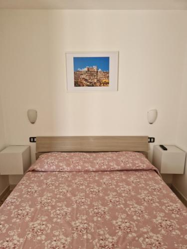 ein Schlafzimmer mit einem Bett und einem Bild an der Wand in der Unterkunft Architello Casa Vacanze in Corigliano Calabro