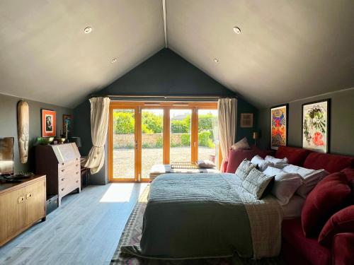 um quarto com uma cama grande e um sofá vermelho em Quirky Luxury Barn Sleeps 8, Pet Friendly em Calne