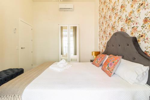 a bedroom with a large white bed with a large headboard at Casa Palacio Rufina & Jardines in Jerez de la Frontera