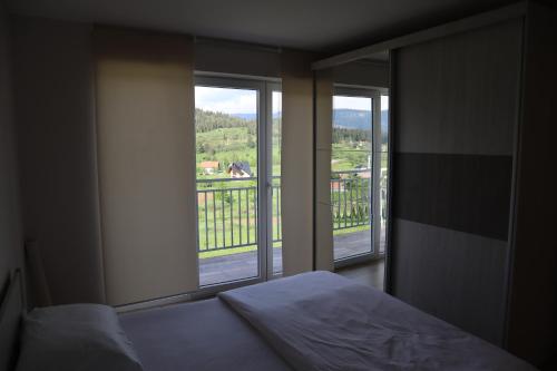 a bedroom with a bed and two windows with a view at Lotus Villas in Travnik